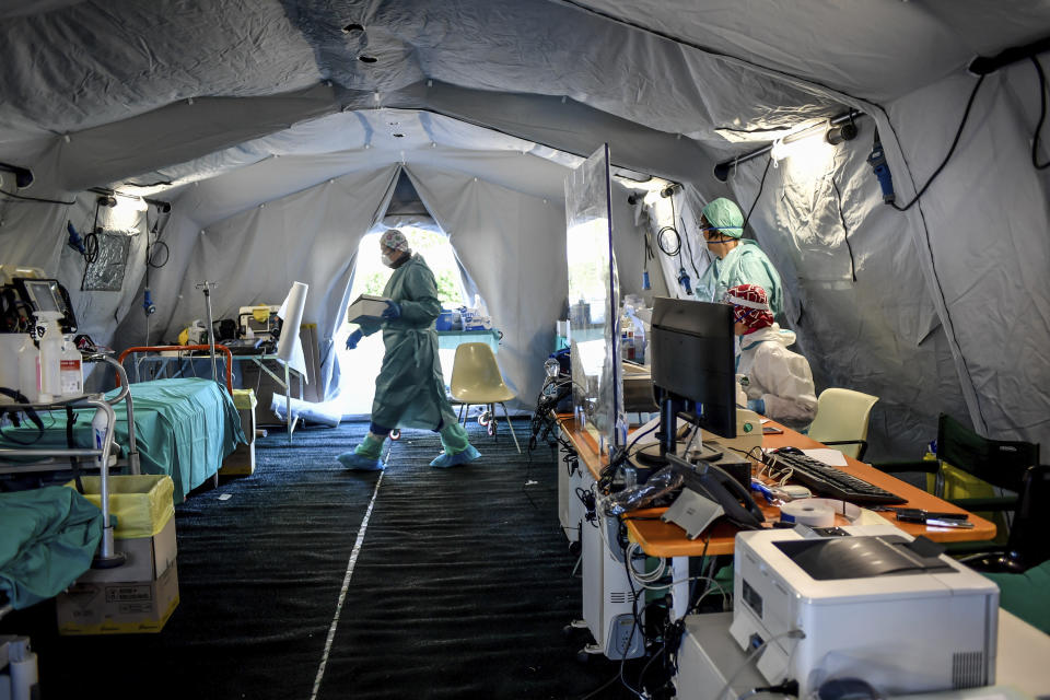 Medical personnel works inside one of the emergency structures that were set up to ease procedures outside the hospital of Brescia, Northern Italy, Tuesday, March 10, 2020. For most people, the new coronavirus causes only mild or moderate symptoms, such as fever and cough. For some, especially older adults and people with existing health problems, it can cause more severe illness, including pneumonia. (Claudio Furlan/LaPresse via AP)