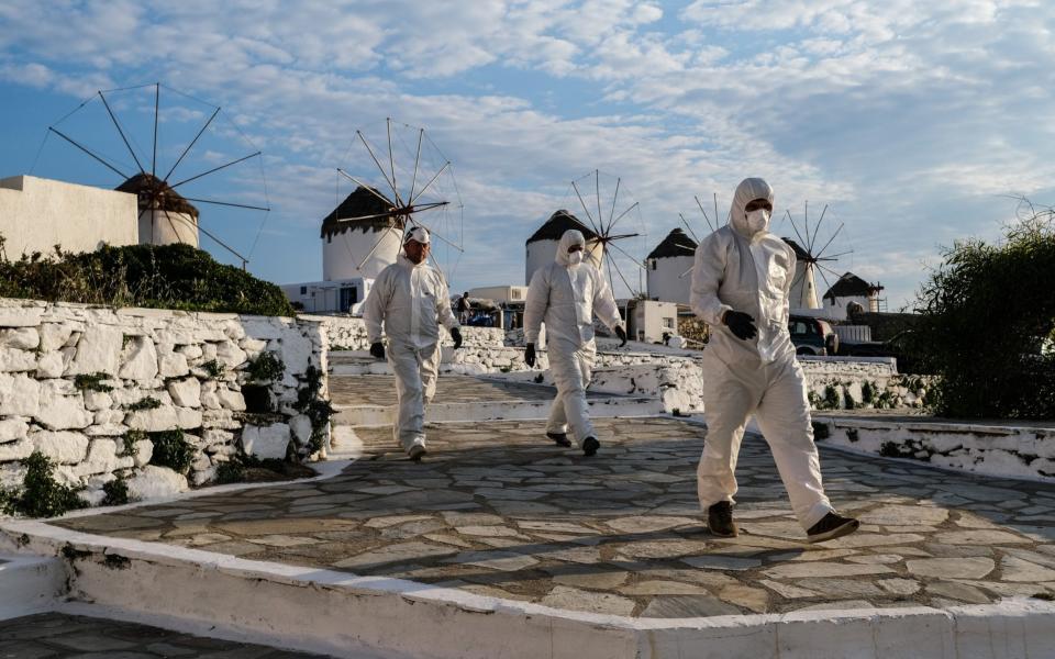 Contractors dressed in personal protective equipment (P.P.E.) remove debris from a home in the Little Venice neighborhood on May 25, 2020 in Mykonos, Greece - Getty