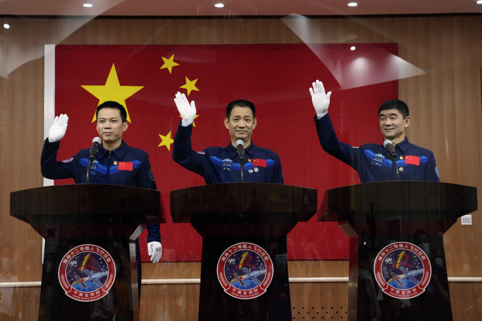 Chinese astronauts, from left, Tang Hongbo, Nie Haisheng, and Liu Boming wave during a press conference at the Jiuquan Satellite Launch Center ahead of the Shenzhou-12 launch from Jiuquan in northwestern China, Wednesday, June 16, 2021. China plans on Thursday to launch three astronauts onboard the Shenzhou-12 spaceship, who will be the first crew members to live on China's new orbiting space station Tianhe, or Heavenly Harmony from the Jiuquan Satellite Launch Center in northwest China. (AP Photo/Ng Han Guan)