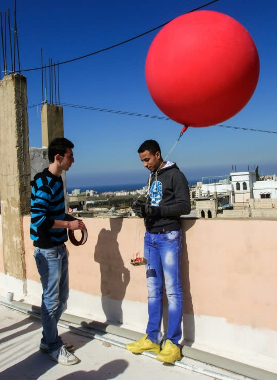 Firas Ismail (L) and Mustafa Dakhloul fix a cheap camera to a balloon to take aerial shots of the Burj al-Shamali refugee camp, in Lebanon, to make a map for camp residents