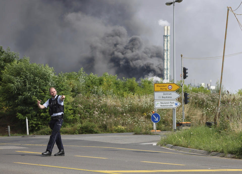 A police officer blocks an access road to the Chempark in Leverkusen, Germany, Tuesday, July 27, 2021 after an explosion in which the emergency services were in large-scale operation to tackle. (Oliver Berg/dpa via AP)