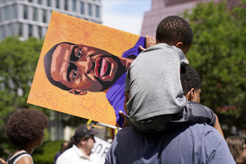 A young boy holds a George Floyd poster as he sits on a shoulder after former Minneapolis police officer Derek Chauvin was sentenced to 22 1/2 years in prison for the May 2020 murder of Floyd, Friday, June 25, 2021, in Minneapolis. (AP Photo/Jim Mone)