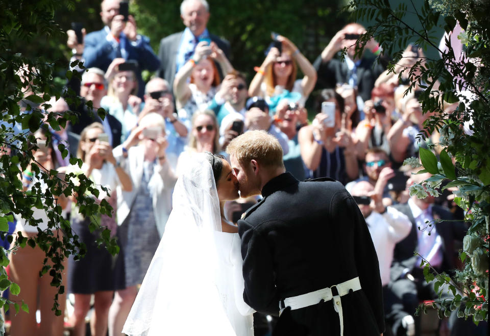 TOPSHOT - Britain's Prince Harry, Duke of Sussex kisses his wife Meghan, Duchess of Sussex as they leave from the West Door of St George's Chapel, Windsor Castle, in Windsor, on May 19, 2018 after their wedding ceremony. (Photo by Danny Lawson / POOL / AFP)        (Photo credit should read DANNY LAWSON/AFP/Getty Images)