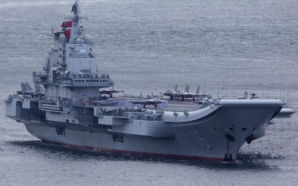 Members of the People's Liberation Army (PLA) Navy stand on the Liaoning aircraft carrier as it sails into Hong Kong, china, on Friday, July 7, 2017.  - Credit: Bloomberg