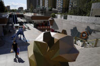 A woman carrying groceries walks by a map showing the Evergrande development projects in China, at an Evergrande city plaza in Beijing, Tuesday, Sept. 21, 2021. Global investors are watching nervously as the Evergrande Group, one of China's biggest real estate developers, struggles to avoid defaulting on tens of billions of dollars of debt, fueling fears of possible wider shock waves for the Chinese financial system. (AP Photo/Andy Wong)