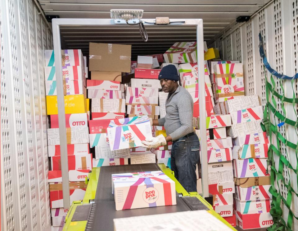 Ein Mitarbeiter lädt im Hermes Rücksendezentrum Pakete mit Retouren aus einem Container auf ein Transportband.  - Copyright: Foto: Daniel Bockwoldt/dpa