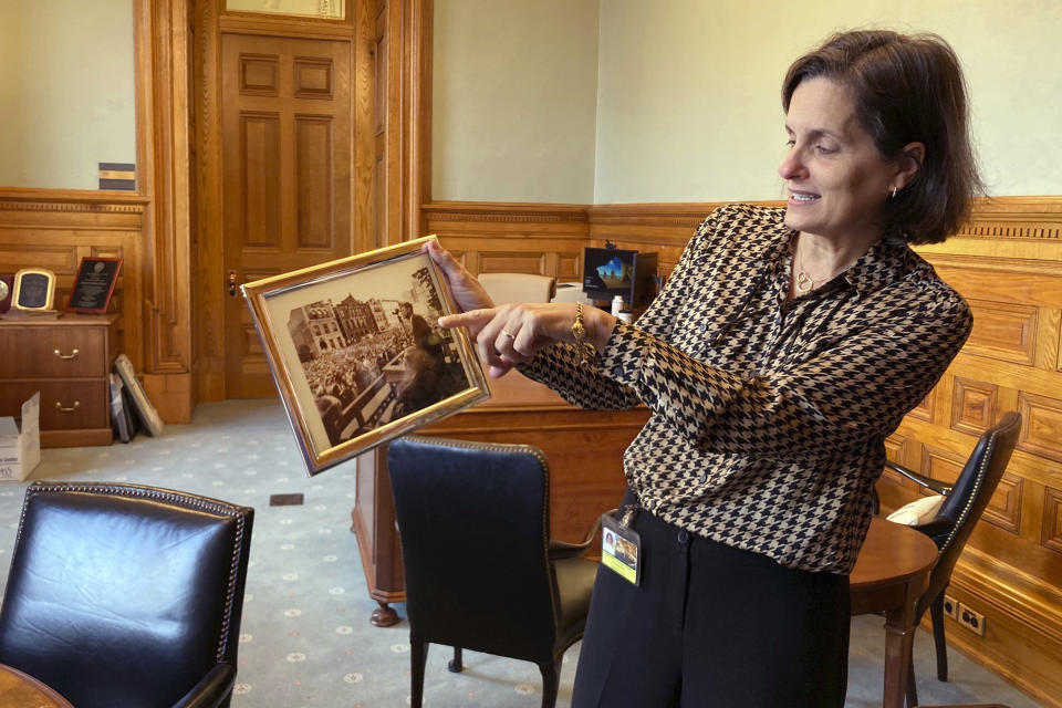 New Jersey Treasurer Elizabeth Muoio shows a photograph of former President John F. Kennedy, Wednesday, March 22, 2023, in Trenton, N.J., speaking at the statehouse building from roughly just outside the spot where her new office is located. The building has been reopened and reoccupied by the governor's and other executive staff after a nearly six year, $300-million renovation. (AP Photo/Mike Catalini)