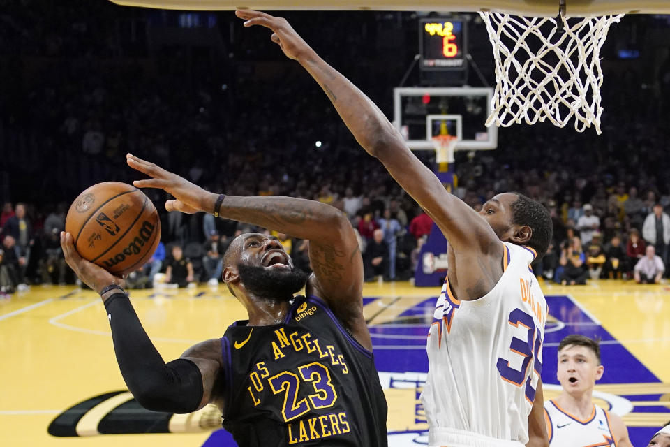 LeBron James, izquierda, de los Lakers de Los Ángeles, dispara con la presión defensiva de Kevin Durant, de los Suns de Phoenix, durante la segunda mitad del juego de baloncesto de la NBA en el torneo In-Season, en los cuartos de final, el martes 5 de diciembre de 2023, en Los Ángeles. (AP Foto/Mark J. Terrill)