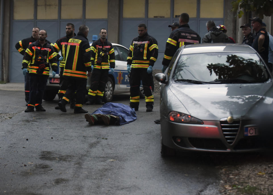 Bomberos de pie junto a un cadáver en el lugar donde un hombre mató a varias personas, el viernes 12 de agosto de 2022, en Cetiña, a unos 30 kilómetros al oeste de Podgorica, Montenegro. (AP Foto/Risto Bozovic)