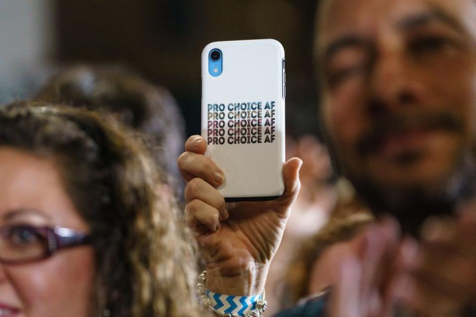 Un asistente de un evento de campaña a favor de los demócratas de Georgia, el 28 de octubre de 2022 en College Park, Georgia, con un celular con una funda a favor del aborto.