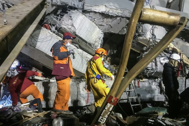 Rescue workers search through rubble for victims' belongings to help with identification in the southern Taiwanese city of Tainan early on February 9, 2016