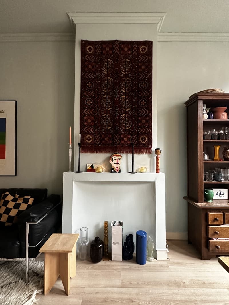 Living room and dining room with black leather vintage sofa, vintage rugs, and vintage art on the walls