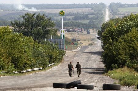 Ukrainian servicemen walk along a road as they guard a checkpoint near the eastern Ukrainian town of Debaltseve, August 16, 2014. REUTERS/Valentyn Ogirenko