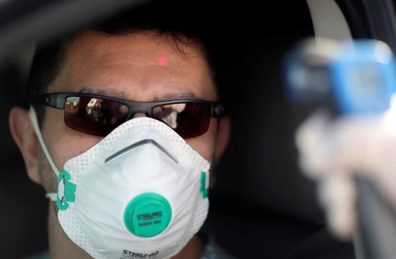 A health worker takes the temperature of a driver for precaution due to coronavirus disease (COVID-19), in Buenos Aires