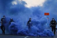 FILE - In this May 30, 2020, file photo, police in riot gear walk through a cloud of blue smoke as they advance on protesters near the Minneapolis 5th Precinct in Minneapolis. Former Minneapolis police Officer Derek Chauvin faces decades in prison when he is sentenced Friday, June 25, 2021, following his murder and manslaughter convictions in the death of George Floyd. Floyd's death, filmed by a teenage bystander as Chauvin pinned Floyd to the pavement for about 9 and a half minutes and ignored Floyd's "I can't breathe" cries until he eventually grew still, reignited a movement against racial injustice that swiftly spread around the world and continues to reverberate.(AP Photo/John Minchillo, File)