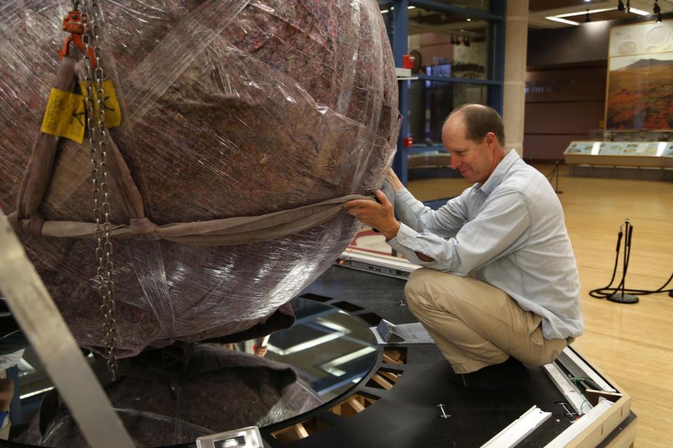 Leo Landis, curator at the State Historical Museum in Des Moines, assists with installation of The Des Moines Register's globe at the museum in December 2013. The globe stood in the Register's lobby from 1950 to 2013, a symbol of the Register's delivery of news from around the world to its readers in Iowa.