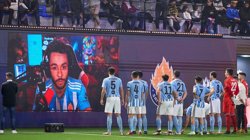 The streamer TheGrefg is seen speaking to his team, Saiyans FC, from a screen at the Cupra Arena.