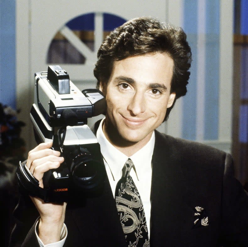 Closeup of Bob Saget holding a camera