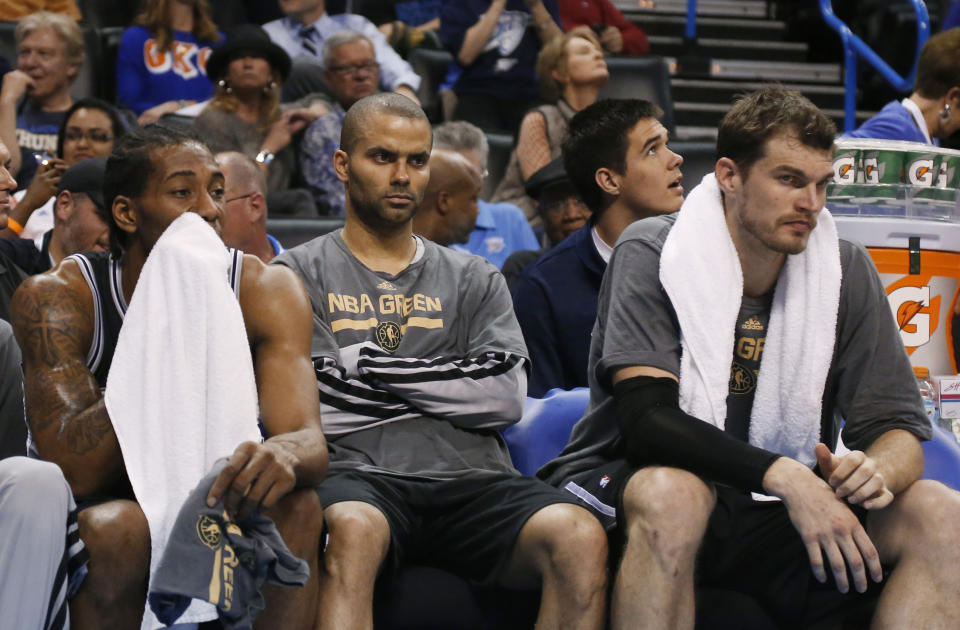 San Antonio Spurs forward Kawhi Leonard, left, guard Tony Parker, center, and center Tiago Splitter watch from the bench in the fourth quarter of an NBA basketball game against the Oklahoma City Thunder in Oklahoma City, Thursday, April 3, 2014. Oklahoma City won 106-94. (AP Photo/Sue Ogrocki)