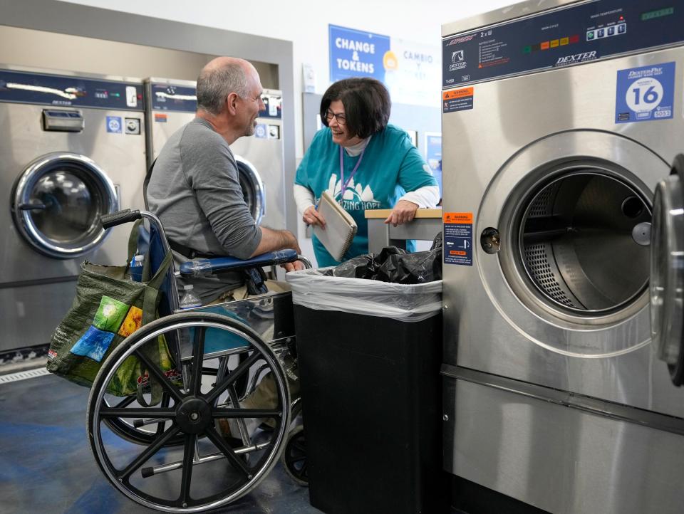 Jo Murray, a volunteer with Maximizing Hope, talks to John Woodley while he waits for his laundry. Woodley expects he’ll start spending $10 to $15 a week on laundry while Maximizing Hope's laundry events are on hiatus.