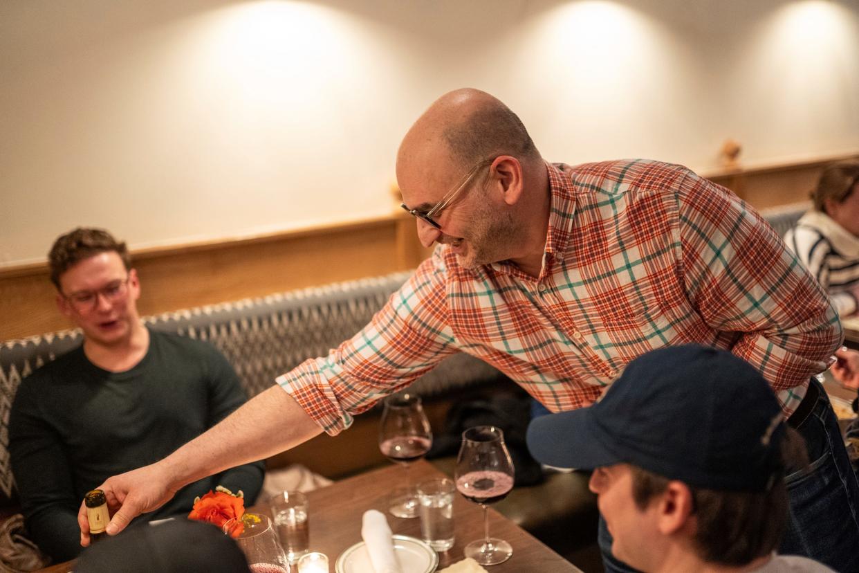 Alpino owner David Richter sets a bottle of wine on the table for customers at his restaurant in Detroit's Corktown neighborhood on Friday, February 16, 2024. The restaurant focuses on a cuisine inspired by the Alps and does so in a warm, elegant environment paired with excellent hospitality.