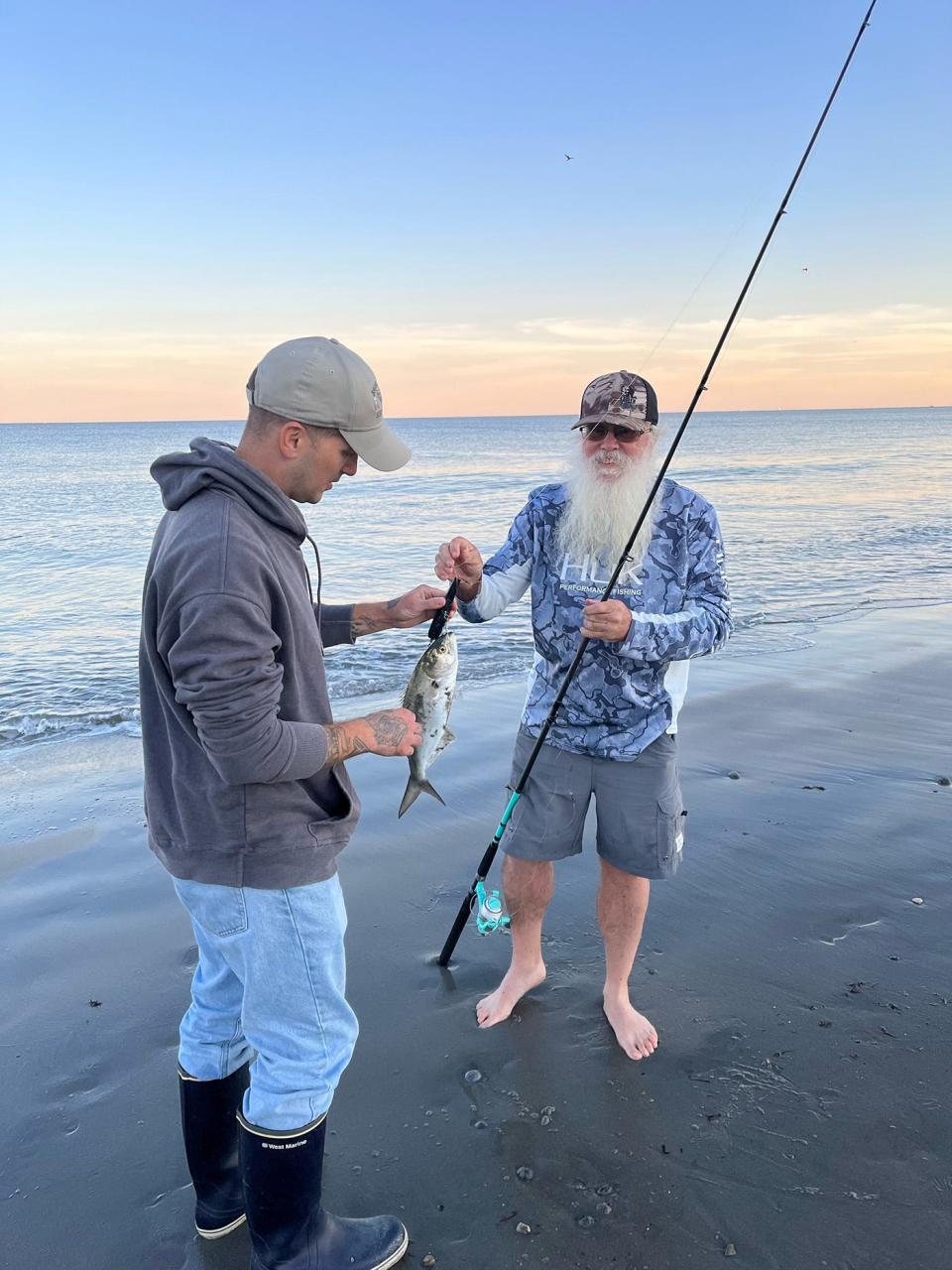 Justyn Charon of the Vet Center admires a striper caught by Ed Bowen at a recent surfcasting event at Scarborough Beach.