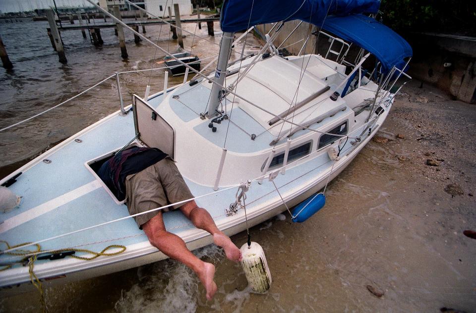 The 1997-98 Dry season was an El Nino season and Steve Ostrander had to secure an anchor line on a 22-foot sailboat that washed ashore at the Palm Beach Sailing Club in West Palm Beach, October 3, 1998. (Sherman Zent / The Palm Beach Post)