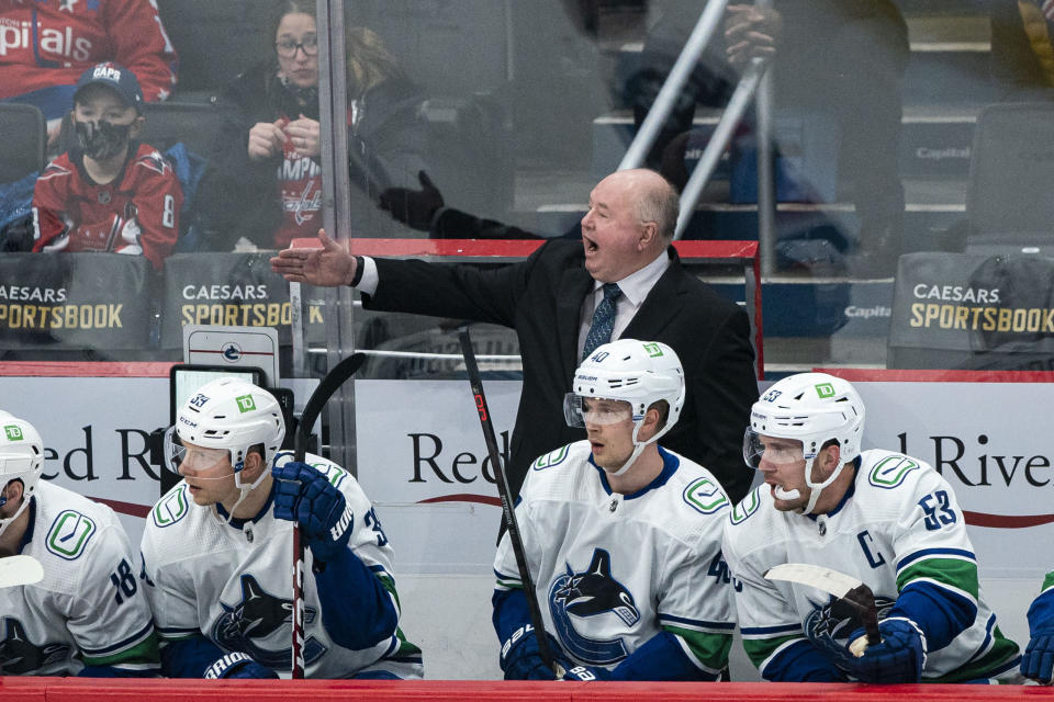 Vancouver Canucks head coach Bruce Boudreau, top, advises his team during the first period of an NHL hockey game against the Washington Capitals, Sunday, Jan. 16, 2022, in Washington. (AP Photo/Al Drago)