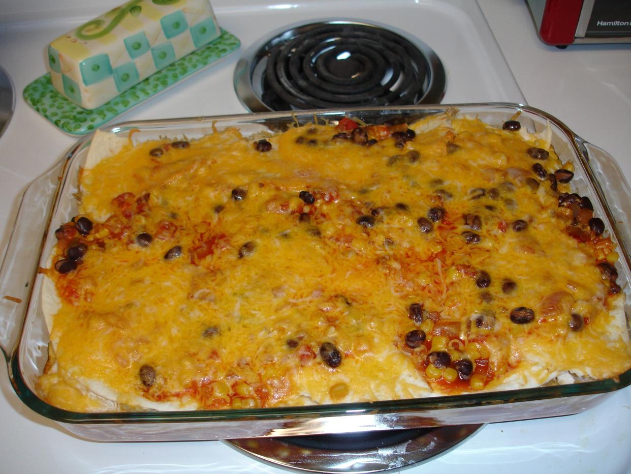 Enchilada casserole in a large rectangular clear glass pan.