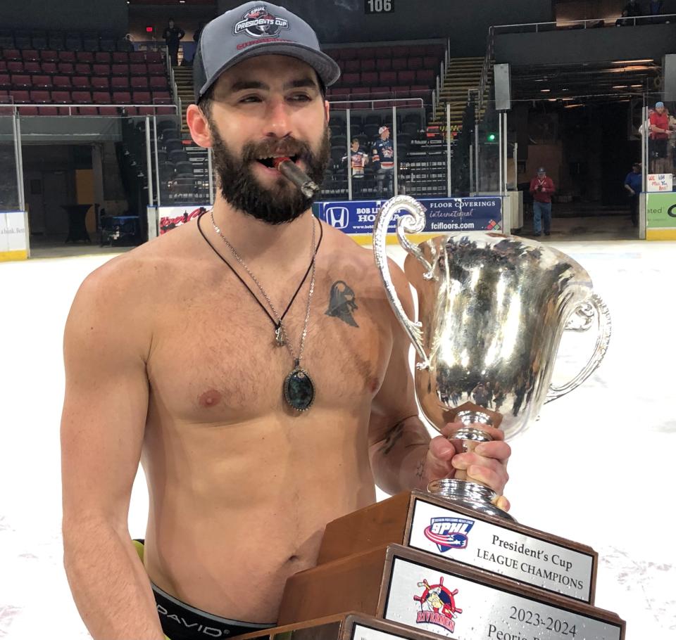 Peoria Rivermen center Joe Drapluk holds the President's Cup while while enjoying a championship victory cigar and wearing the team's lucky crystal around his neck at Carver Arena on Sunday, April 28, 2024.