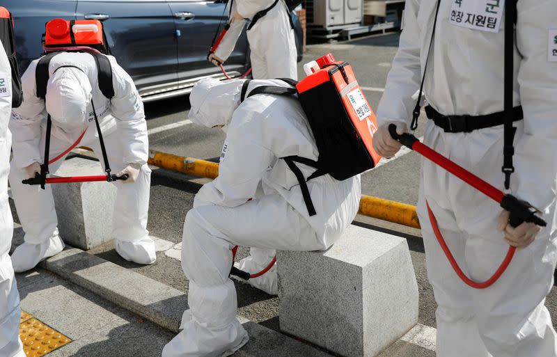 South Korean soldiers wearing protective gear take a break after sanitizing a street in front of the city hall after the rapid rise in confirmed cases of the novel coronavirus disease of COVID-19 in Daegu