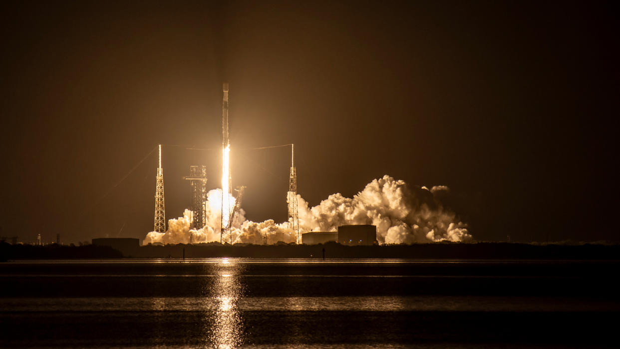  A black-and-white spacex falcon 9 rocket launches into a night sky. 