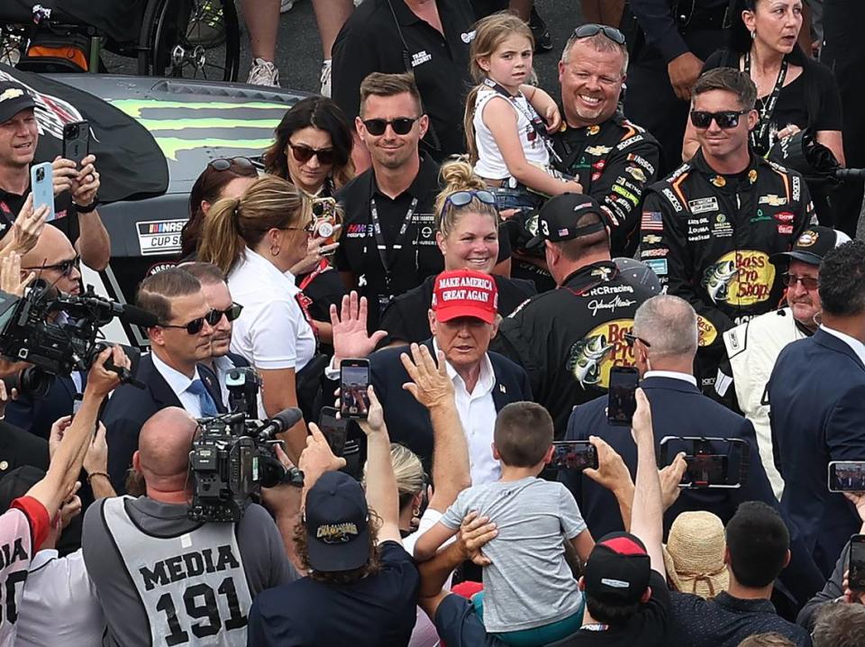 Former President Donald Trump, center, waves to fans along pit road at Charlotte Motor Speedway prior to the running of the Coca-Cola 600 in Concord, NC on Sunday, May 26, 2024.