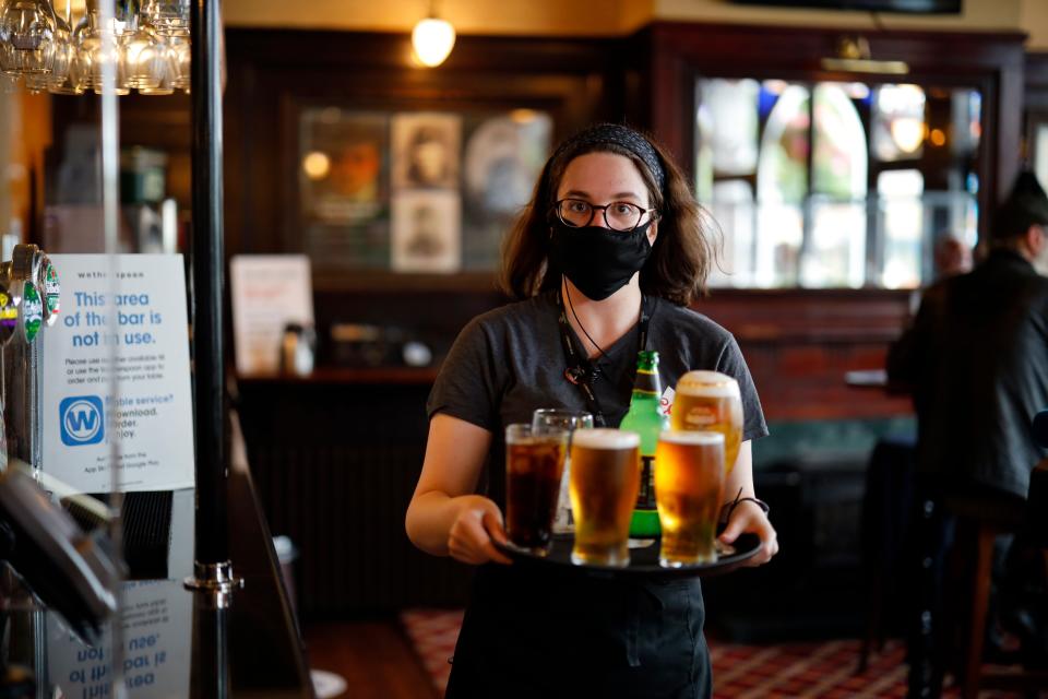 A member of bar staff wearing a face mask carries drinks inside the Wetherspoon pub, Goldengrove in Stratford in east London, on July 4. (Photo: TOLGA AKMEN via Getty Images)