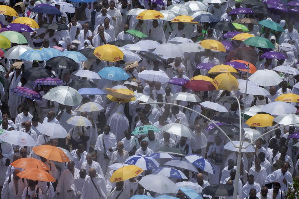 Cooling water sprayers bring down the temperatures as Muslim pilgrims on their way to perform Friday Prayers at Namira Mosque in Arafat, on the second day of the annual hajj pilgrimage, near the holy city of Mecca, Saudi Arabia, Friday, July 8, 2022. (AP Photo/Amr Nabil)