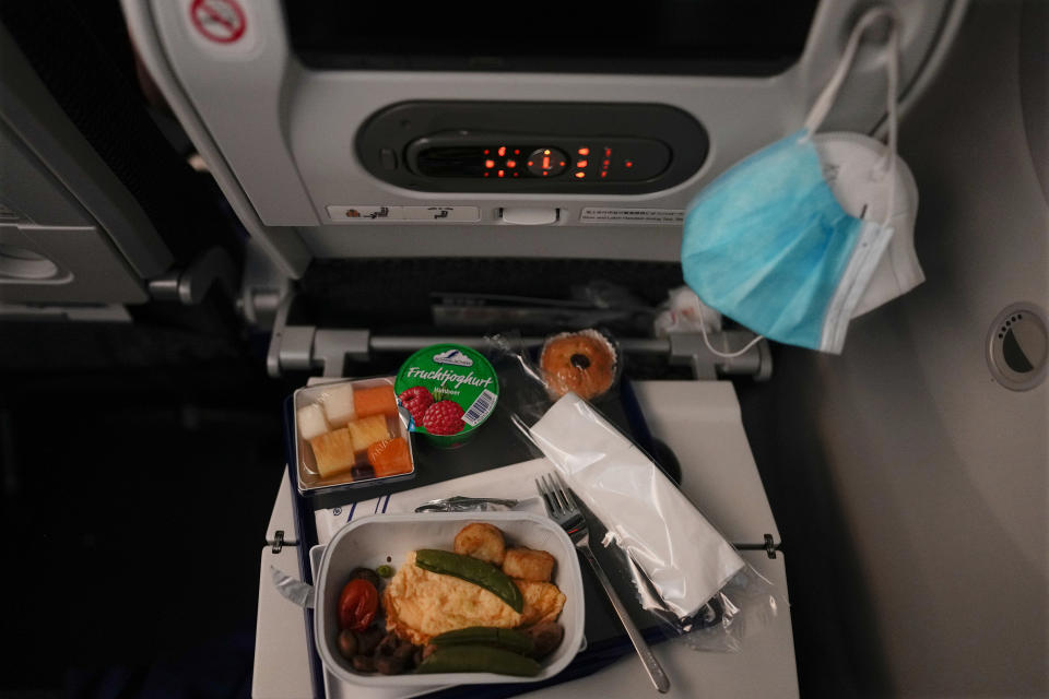 A breakfast sits in front of face masks on a tray table during a flight to Tokyo from Frankfurt, Germany, Monday, July 19, 2021. (AP Photo/Natacha Pisarenko)