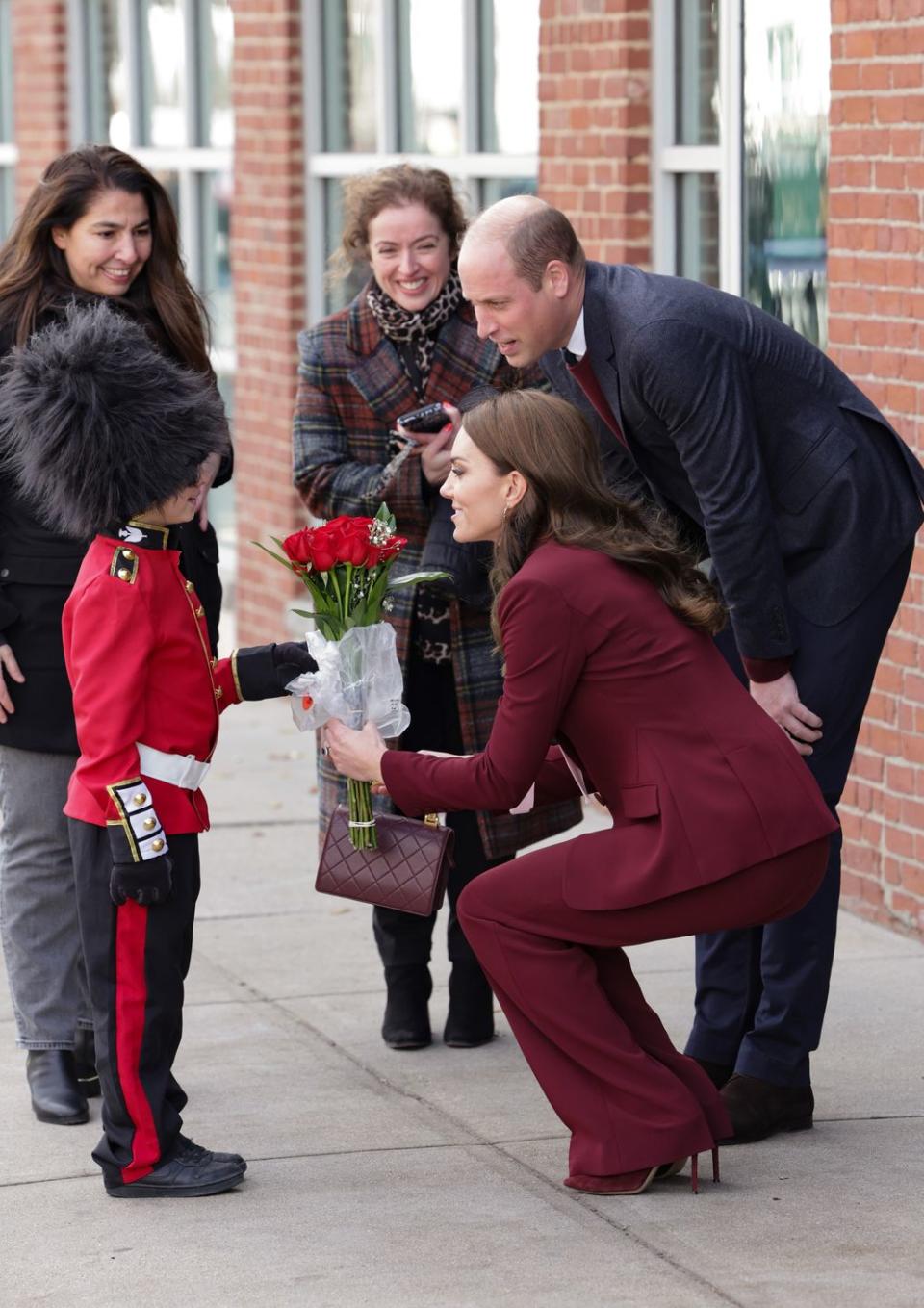 <p>Kate and William accept flowers from a little boy dressed up as the King's Guard.</p>