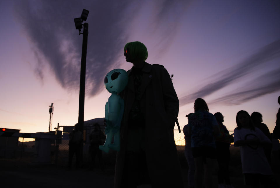 Chase Hansen holds an inflatable alien near an entrance to the Nevada Test and Training Range near Area 51, Friday, Sept. 20, 2019, near Rachel, Nev. People came to visit the gate inspired by the "Storm Area 51" internet hoax. (AP Photo/John Locher)