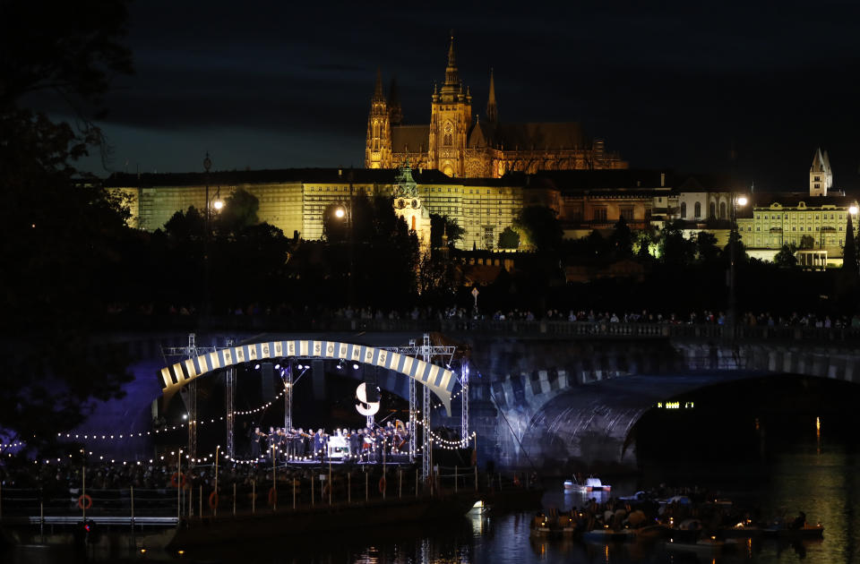 People enjoy a concert of British violinist Daniel Hope set on a floating stage on the Vltava river in Prague, Czech Republic, Saturday, Sept. 19, 2020. The Czech Republic has been been facing the second wave of infections of COVID-19. The number of new confirmed coronavirus infections has been setting new records almost on a daily basis. The Prague Castle is in the background. (AP Photo/Petr David Josek)