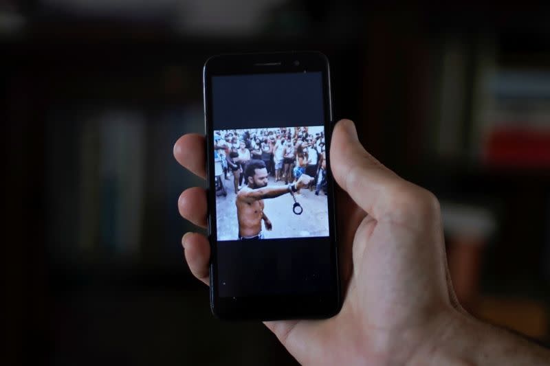 Un hombre que no quiso ser identificado muestra en su teléfono móvil una imagen difundida en las redes sociales del rapero Maykel Castillo con esposas sujetas a una de sus muñecas, en La Habana, Cuba.