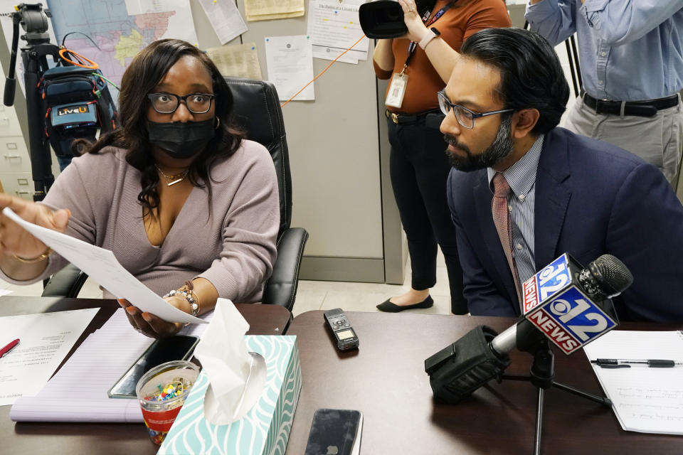 Commissioner RaToya Gilmer McGee, left, shows a ballot styles report to Amir Badat, an attorney for the NAACP Legal Defense Fund, during a meeting between the Hinds County Election Commission and a coalition of national and local civil rights organizations, Monday, Dec. 18, 2023, in Jackson, Miss. The commissioners said ballot shortages, technical mishaps and insufficient training were some of the factors that hampered voting in Mississippi's largest county during the Nov. 7 general election. (AP Photo/Rogelio V. Solis)