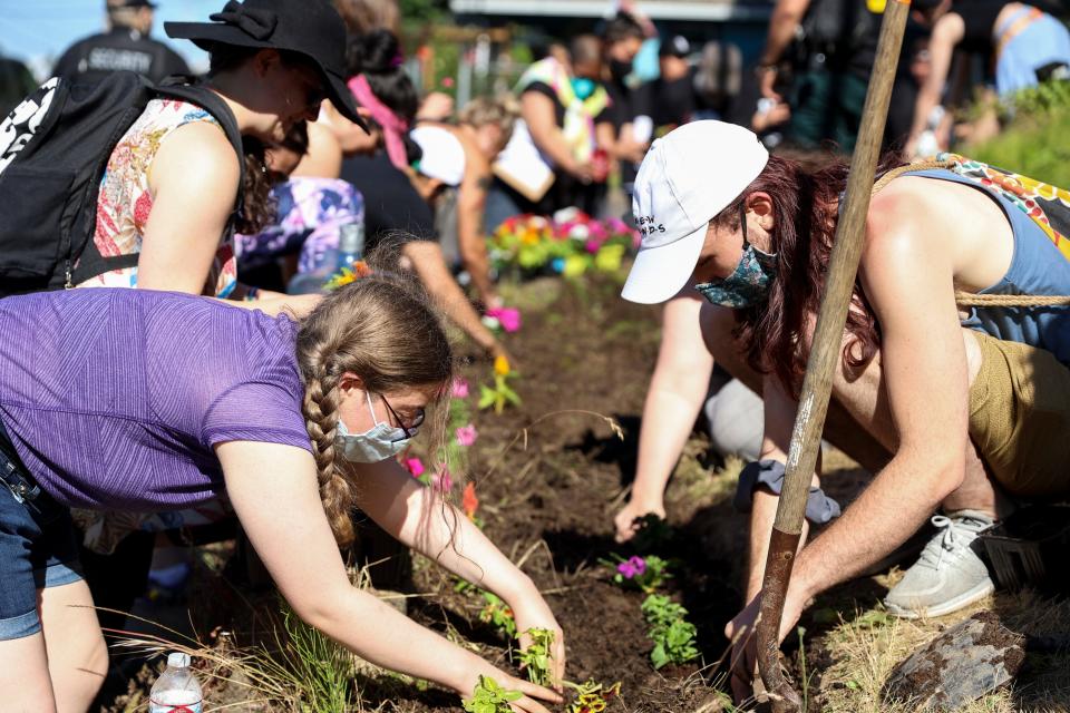 Community members and Latinos Unidos Siempre plant flowers in front of Robert High School Thursday in hopes of making something beautiful. The effort was part of an advocacy event for more resources for mental health services in schools.