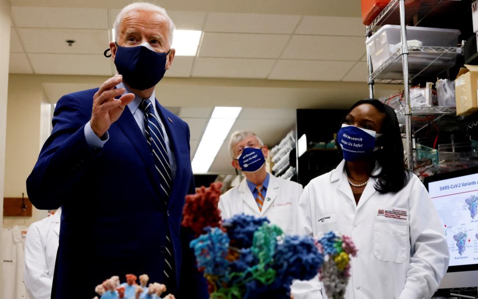 President Joe Biden speaks next to an NIH staff member as NIH Director Francis Collins listens during a visit to the Viral Pathogenesis Laboratory at the National Institutes of Health - REUTERS/Carlos Barria