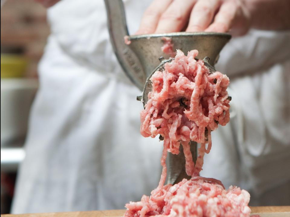 person grinding meat in a meat grinder