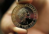 A gallery assistant holds a 2-pound coin with the new portrait of Britain's Queen Elizabeth following it's unveiling at the National Portrait Gallery in London March 2, 2015. This is the fifth portrait of the Queen to be used on a British coin during her reign. REUTERS/Suzanne Plunkett (BRITAIN - Tags: ROYALS BUSINESS)