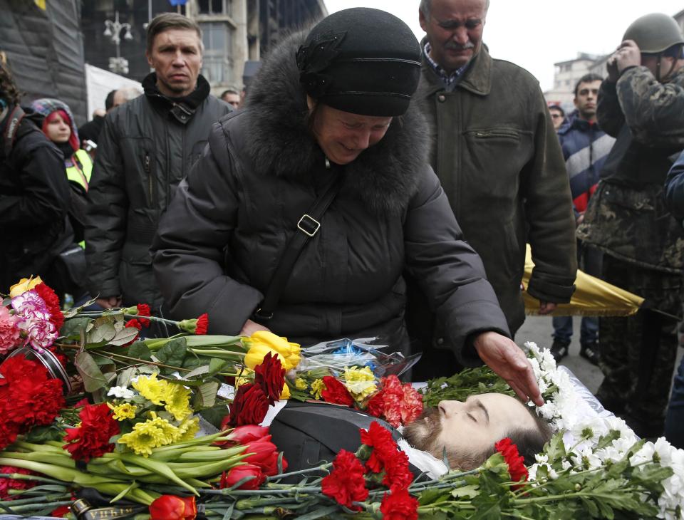 A woman mourns near a coffin with the body of a man during a funeral ceremony in Kiev