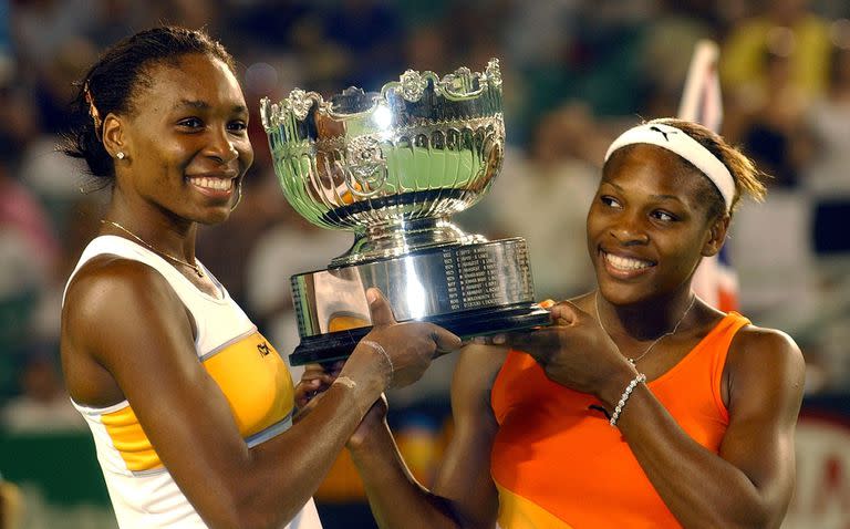 Venus Williams y su hermana Serena sostienen el trofeo después de ganar la final de dobles femeninos contra Virginia Ruano Pascual de España y Paola Suárez de Argentina en el Torneo Abierto de Tenis de Australia en Melbourne, el 24 de enero de 2003.