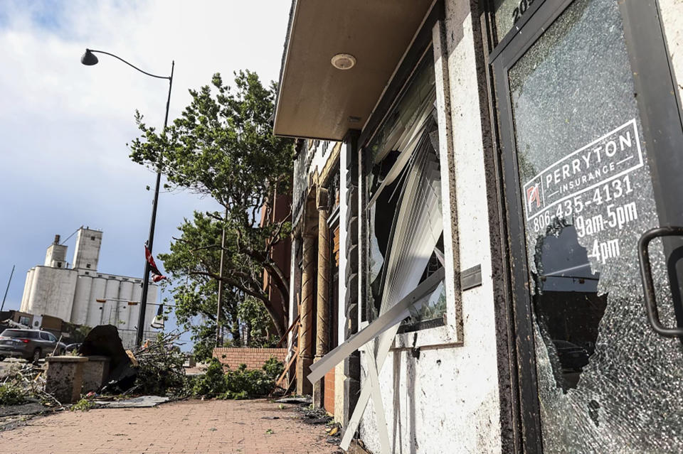 A cracked storefront window in downtown Perryton, with planks poking out of a broken window behind.