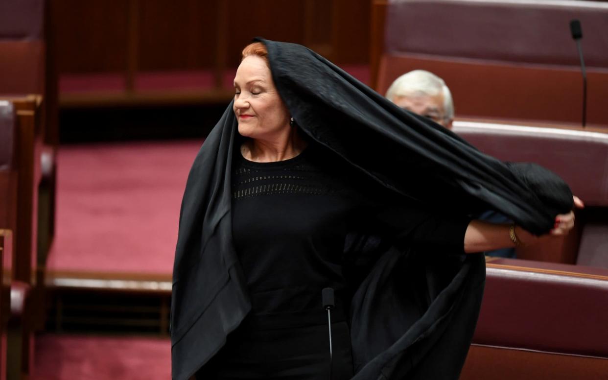 Senator Pauline Hanson pulls off a burqa in the Senate chamber at Parliament House in Canberra, Australia - REUTERS