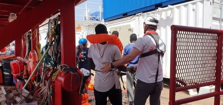 Rescued migrant and a staff member shake hands aboard the Ocean Viking in this handout picture